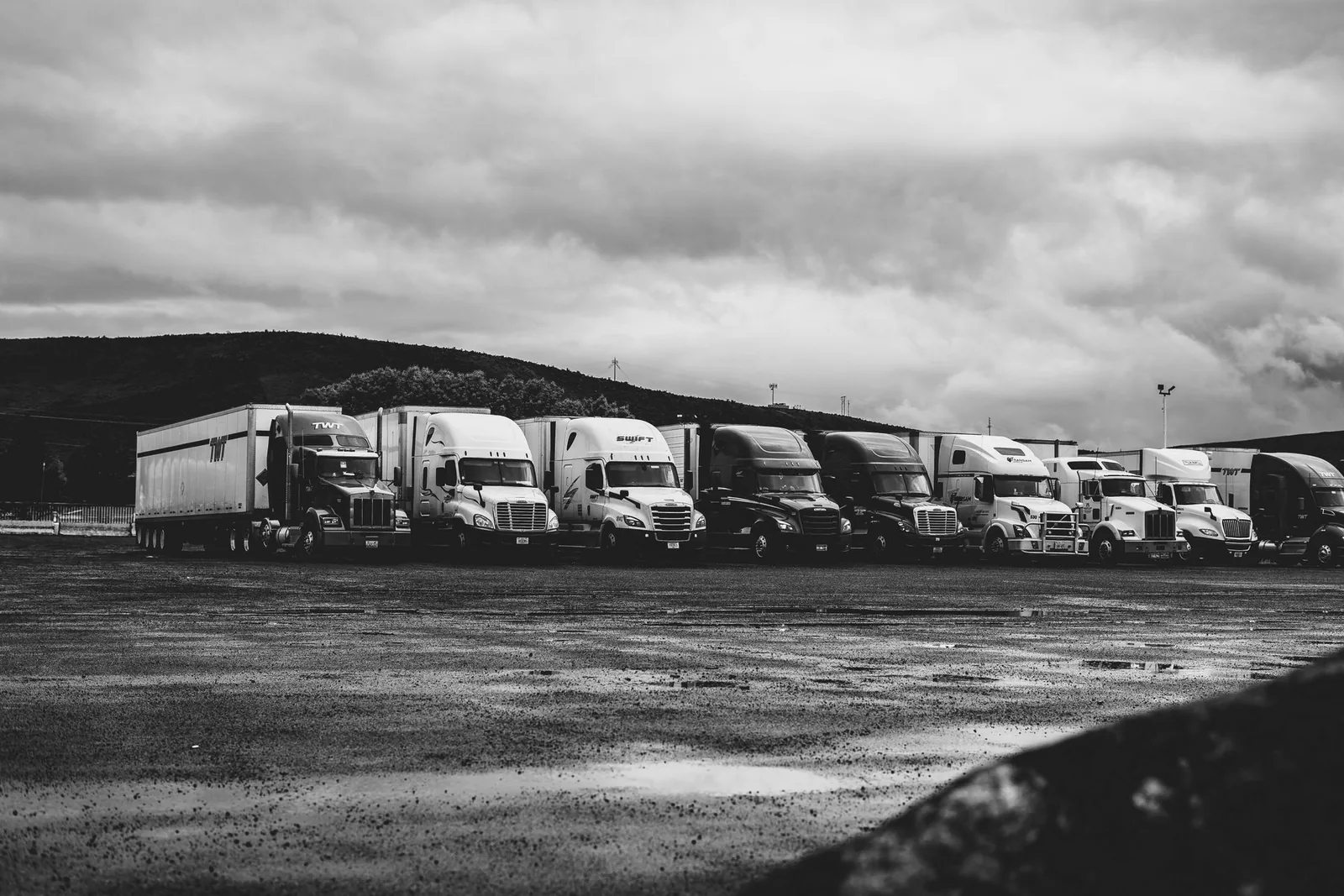 A row of heavy goods vehicles parked at a depot under an overcast sky