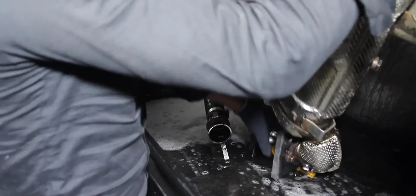 Technician removing a diesel particulate filter from beneath a vehicle