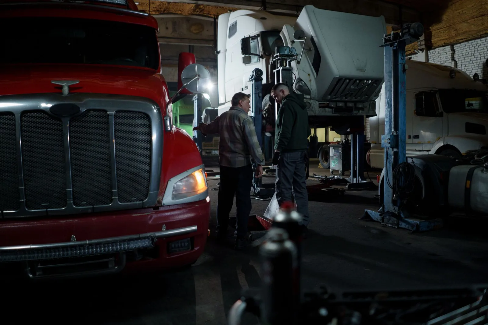 Commercial trucks in a workshop bay with technicians working between them