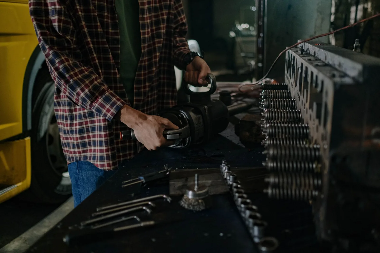 Close work on a heavy vehicle component at a bench, tools laid out alongside